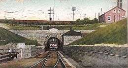 A postcard with a frontal view of a train emerging from a tunnel