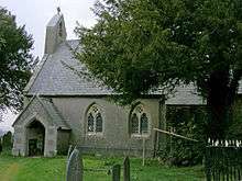 A small church with a rendered nave and west single bellcote