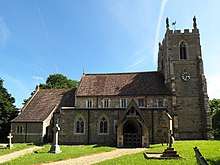 A stone church from the north showing part of the chancel, the nave with clerestory, a north porch, and an embattled tower with a statue on the top of each corner