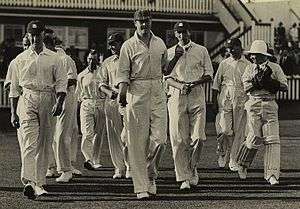 A group of cricketers coming onto the field