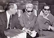 Two women wearing sunglasses seated next to a man