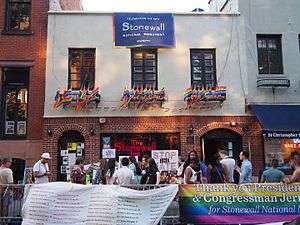 A color photograph of the Stonewall Inn, taken in the summer of 2016; the doorway and windows are decorated with rainbow flags