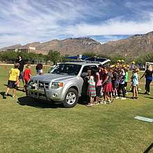 Students looking at self-driving car on school field.