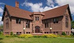 Sumner, a Tudor Revival library of red brick on a sunny summer day