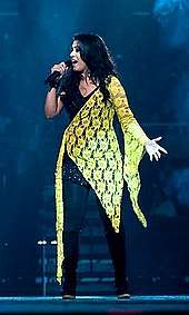 Sunidhi Chauhan performing on stage wearing a black and yellow dress