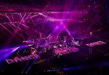 A faraway image of a stage with purple lights flashing from all around on it.