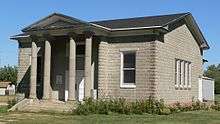 One-story concrete-block building, fairly small; pedimented porch with four columns