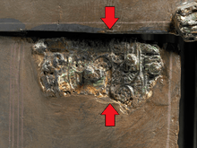 Close-up colour photograph of two joining fragments on dexter cheek guard which together complete a hinge. The fragment on the left was discovered in 1967 during re-excavations at Sutton Hoo.