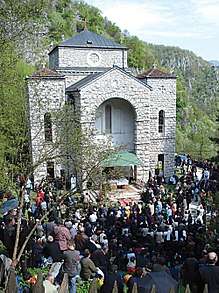 Mountainside stone church with a crowd outside