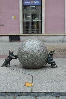Sisypher dwarves sculpture by Tomasz Moczek. Two small bronze figures stand either side of a stone sphere.