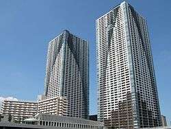 Ground-level view of two similar rectangular high-rises; each building is painted to have curved sections of color on the primarily white facades