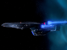 An oblong, blue-grey starship with an oval hull and two flanking, glowing engines