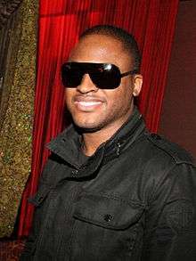 A man wearing sunglasses smiling to the camera.