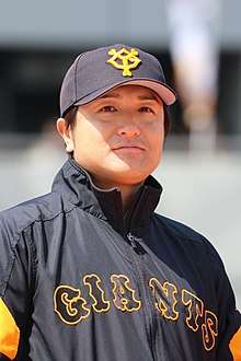 Japanese man wearing a black and orange hat and jacket