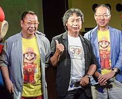 An image of the three integral staff who worked on the game. From left to right is director Takashi Tezuka, producer Shigeru Miyamoto, and composer Koji Kondo.