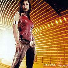 A body shot of a Japanese woman (Kumi Koda) standing in the middle of an underground tunnel, orange-tinted while the artist and song title are placed at the bottom corner.
