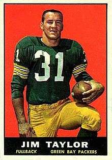 A color photo of Jim Taylor kneeling holding a football in his hand. The text "Jim Taylor, Fullback, Green Bay Packers" is printed in a black bar below the photo.