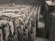 A large number of lined up human sculptures in a pit.
