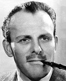 Terry-Thomas with slicked back hair, using a cigarette-holder