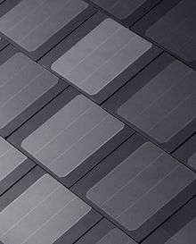 Image of the Tesla Solar Roof tiles, which consist of thin, black roofing shingles with glassy, embedded solar panels.