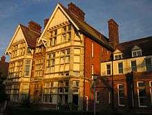 Two 3-story gabled towers of East Kent College, in late sun.