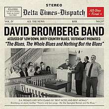 The front page of a newspaper, with a large photo of a courtroom trial. David Bromberg is on the witness stand, being questioned about an electric guitar.