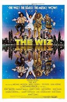 Four characters from the film dancing on top of a logo "THE WIZ". A city skyline just after dusk is seen behind them, and the entire scene is mirrored in water before them. The people are Dorothy, the Scarecrow, the Tin Woodman, and the Lion.