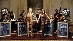  Two female vocalists perform on stage foreground to eight bandmates on the set of Gossip Girl.