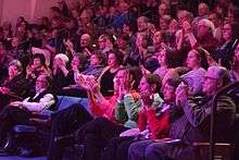Crowd applauding a performance at a live theater.