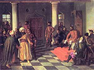 Two bearded men, each wearing a turban, stand before a man who sits on a throne; a dozen people surround them