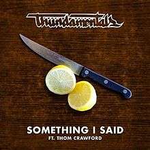 A sharp kitchen knife lies next to a halved lemon. It has a blue-black handle with three rivets. Below is a brown wooden surface. Across the top is a stylised version of the group's name in white bordered lettering. Across the bottom in white, fill-in, block capitals is the title followed by "FT." and the featured singer's name.