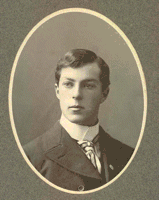 Two-thirds oval portrait of a dignified young man in his twenties. His eyes gaze over the viewer's right shoulder. His dark, straight hair is parted on the right. Around his high collar sits a striped tie, and on his suit a lapel pin.