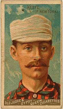 A baseball-card image of a mustachioed man in a red-and-black striped shirt and white pillbox cap