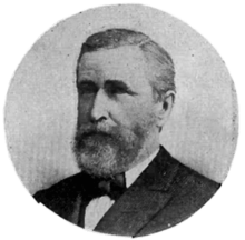 A black and white circular portrait of a Caucasian man in a suit and bow tie.