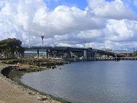 Long distance photograph of a motorway bridge over a body of water.