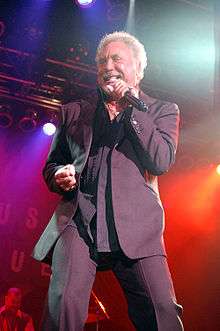 Tom Jones singing into a microphone on stage