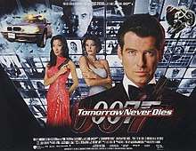 A man wearing an evening dress holds a gun. On his sides are a white woman in a white dress and an Asian woman in a red, sparkling dress holding a gun. On the background are monitors with scenes of the film, with two at the top showing a man wearing glasses holding a baton. On the bottom of the screen are two images of the 007 logo under the title "Tomorrow Never Dies" and the film credits.