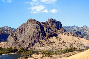 Image of an igneous rock formation with two peaks near a river