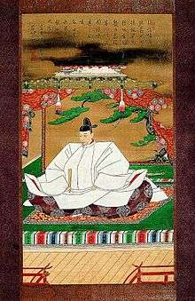 In this artwork a Japanese man in with a black hat and traditional clothing sits on the floor with a closed fan in his right hand