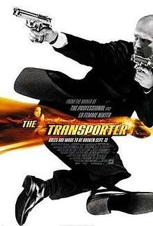 Jason Statham wearing a suit and holding two guns, in black and white.  A band of orange colour with the title The Transporter is overlaid in the middle of the picture.