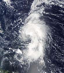 Satellite image of a tropical cyclone in open water. Cloud activity stretches three-fourths the way around the cyclone, and the center is partially exposed.