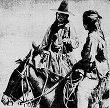 Black and white image of two men on horse back