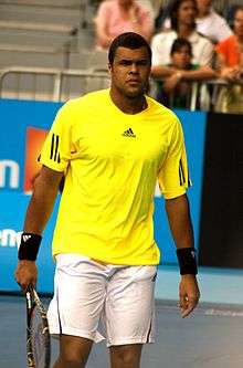 Tsonga in a yellow shirt looking into the camera.