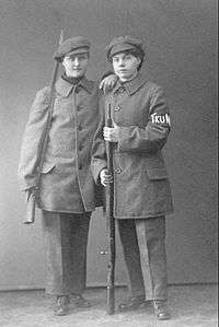 Two young women standing in uniform, each with a rifle