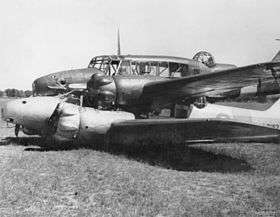 Side view of two military monoplanes lying wheels up on a field, one atop the other