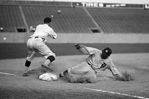 A baseball player slides into third base as an opposing player attempts to tag him