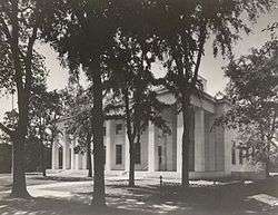 Building with columns behind trees.