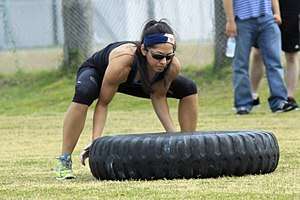 Woman lifting a 200 pound tyre - bent knees essential to avoid back strain.