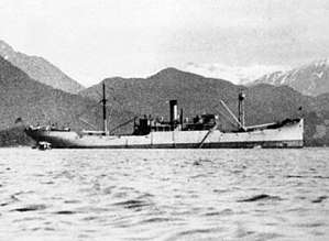 Side view of a ship upon water, with mountains visible in the background
