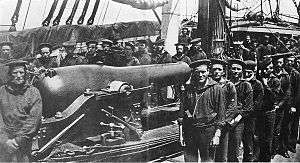 A group of twenty-six sailors posing around a rifled naval cannon